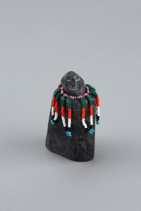 Image: Beaded figure with necklace of white, orange, green and other beads streaming over shoulders